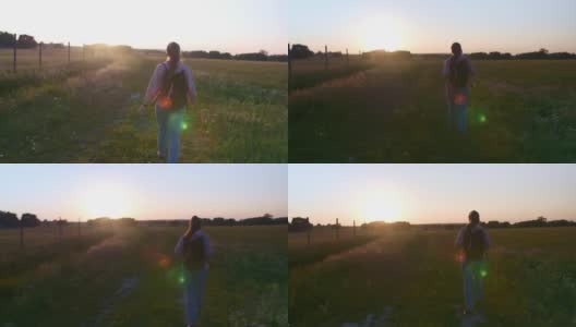 女孩游客在夏天散步在一个田野傍晚日落。高清在线视频素材下载