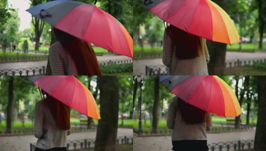 一个不认识的女人在雨下跑在城市公园的背影。Slowmotion拍摄高清在线视频素材下载