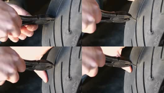 用钳子把摩托车轮胎上的钉子拔出来高清在线视频素材下载