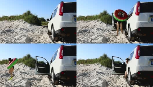 一个女人在沙滩上穿着脚蹼从车里走出来高清在线视频素材下载