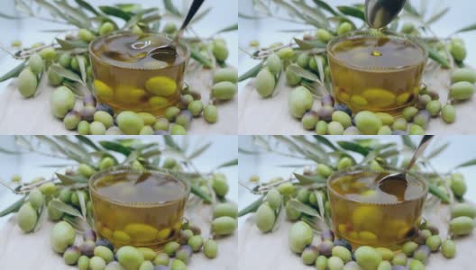 天然橄榄油在透明的碗里用勺子搅拌，里面有成熟的橄榄果，具有抗氧化保健和人体的有机产品，橄榄油用于美容高清在线视频素材下载
