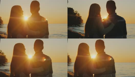 年轻的多民族情侣在日落时拥抱。站在海边。白人女人和亚洲男人高清在线视频素材下载