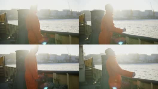 身穿橙色制服的港口工人站在船舷旁。镜头光晕。Slowmotion高清在线视频素材下载
