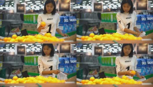 年轻的亚洲女人在杂货店挑选橙子高清在线视频素材下载