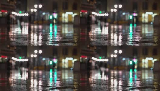 抽象明亮模糊的背景与雨滴，沥青照明路灯和交通灯。身份不明的女孩在雨夜的城市街道上。商店橱窗和街灯在潮湿的路面上发出明亮的照明和反射高清在线视频素材下载