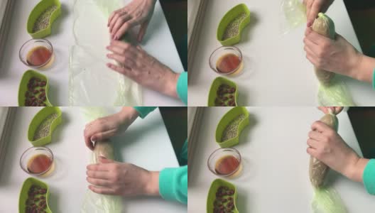 一名妇女用保鲜膜将拌有碎花生、葵花籽和蜂蜜的香肠包裹起来。自制的哈尔瓦做饭。高清在线视频素材下载