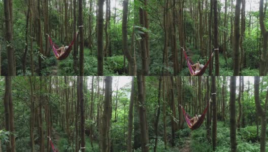 鸟瞰在吊床上放松与行动相机自拍在热带雨林，无人机上升的观点高清在线视频素材下载
