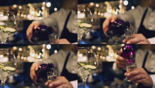 近距离的调酒师测量杜松子酒在一个杯子，把它倒进鸡尾酒杯高清在线视频素材下载