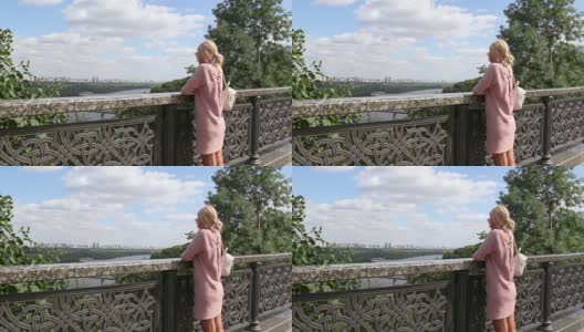 一个女人站在桥上，用一条河看着城市风景高清在线视频素材下载