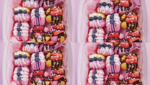 盒子里的马卡龙，手工制作的精美甜品，用巧克力装饰的新鲜草莓和蓝莓甜点，精致的黄色和粉色蛋糕，糖和健康食品高清在线视频素材下载