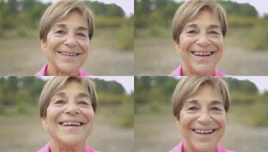 快乐的老年妇女在镜头前微笑在户外的树林-真正的老年人生活方式高清在线视频素材下载