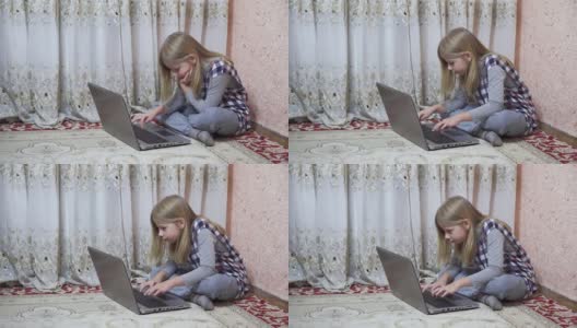 一个中学年龄的小女孩坐在家里的地板上使用笔记本电脑。远程学习时在键盘上打字。高清在线视频素材下载