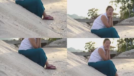 坐在沙滩沙丘上思考生命的亚洲资深女性高清在线视频素材下载