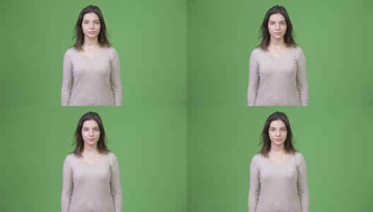 年轻美丽的女人映衬着绿色的背景高清在线视频素材下载