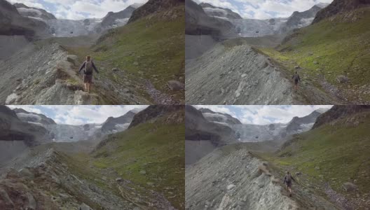 一名年轻男子在瑞士山脊上伸开双臂站立的无人机照片高清在线视频素材下载