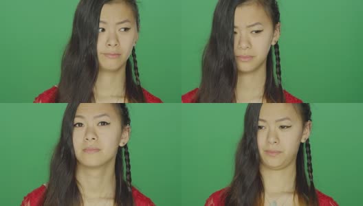 年轻的亚洲妇女环顾四周，做着傻傻的脸，在一个绿色屏幕的工作室背景高清在线视频素材下载