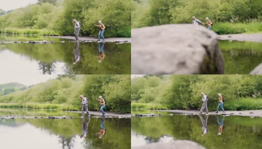 在英国湖区徒步旅行时用垫脚石过河的老年夫妇的慢动作镜头高清在线视频素材下载