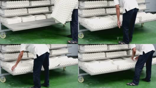 男人在工厂的架子上摆放白色乳胶枕头高清在线视频素材下载