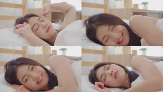 亚洲女人微笑躺在床上的卧室，美丽的日本女性使用放松时间后，在家里醒来。生活方式女性在家里使用放松时间的概念。慢动作镜头。高清在线视频素材下载