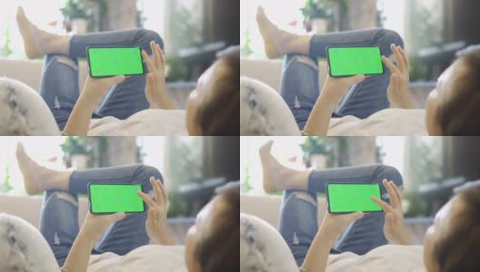 女人在沙发上用绿色屏幕的智能手机高清在线视频素材下载