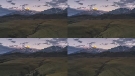 连绵不断的草原后面，雪山的山顶被日出的光芒所照亮高清在线视频素材下载