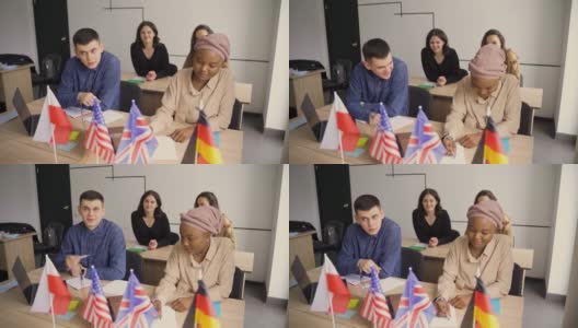 国外学校私学女生。老师用笔记本电脑讲解母语语法。和导师一起准备考试。前面是英国、英国、德国和波兰的国旗。高清在线视频素材下载