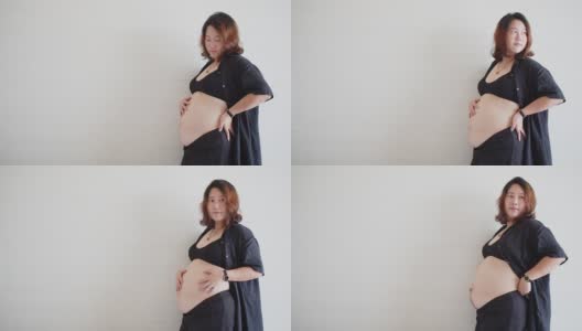 肖像吸引快乐的亚洲孕妇站着触摸她的大肚子与爱，怀孕，为人母，人们和期望的概念高清在线视频素材下载