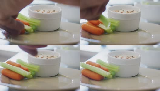 白种人的手把胡萝卜和芹菜整齐地堆在盘子里，旁边是一小碗牧场蘸酱高清在线视频素材下载