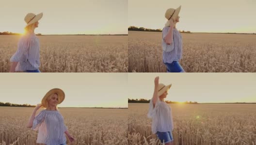 一个戴着帽子的年轻女子正在麦田里享受散步，快乐地向前走着，微笑着。替身拍摄高清在线视频素材下载