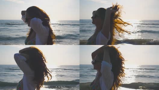 侧面美丽的女孩在比基尼和衬衫走在海边和玩她的头发。快乐的年轻女人戴着太阳镜，在暑假里享受生活。慢动作特写侧视图高清在线视频素材下载