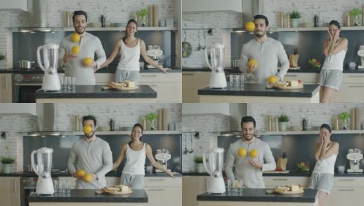 一对美丽的夫妇在做早餐。男人用橘子耍戏法来打动他的女人。高清在线视频素材下载