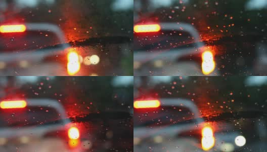 在雨天的天气下开车行驶在城市街道上，雨点落在挡风玻璃上带着模糊的灯光的车辆行驶在交通堵塞的城市道路上高清在线视频素材下载