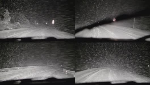 司机POV在积雪覆盖的道路上行驶，初雪飘落。被前灯和雪照亮的路。高清在线视频素材下载