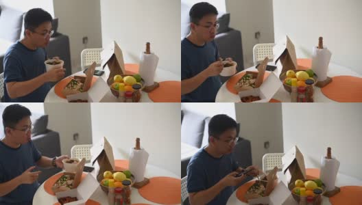 一名亚洲华人中年男子用手机拍下他点的外卖放在餐桌上高清在线视频素材下载
