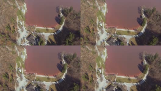 无人机:在空旷的道路上飞行，环绕着一个充满红色水的湖。高清在线视频素材下载