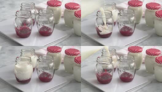 在玻璃罐中加入牛奶混合物，制成自制酸奶。覆盆子果酱在罐子的底部有一种美味的甜味。有机乳制品，健康饮食和可持续发展的理念高清在线视频素材下载