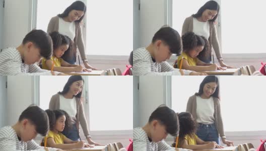 亚洲学校的老师在课堂上帮助学生。年轻女子在学校工作，帮助男孩写作，教育，支持和关心高清在线视频素材下载