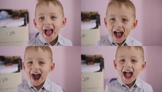 一个金发碧眼的可爱男孩的肖像站在房间的摄像机前，直视着，张开嘴大叫。高清在线视频素材下载