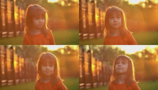 夏日公园里，小女孩微笑着抬头看日落。孩子们在户外的阳光下玩耍。高清在线视频素材下载