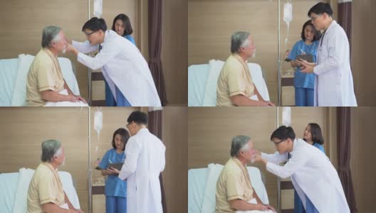 亚洲医生检查老年男子病人的眼睛与护士妇女使用数码平板电脑与老年男子病人在医院的床上交谈高清在线视频素材下载