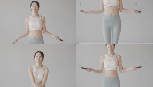 可爱的韩国女性跳绳在白色的工作室，穿着紧身裤和运动背心，精力充沛健康的女性高清在线视频素材下载