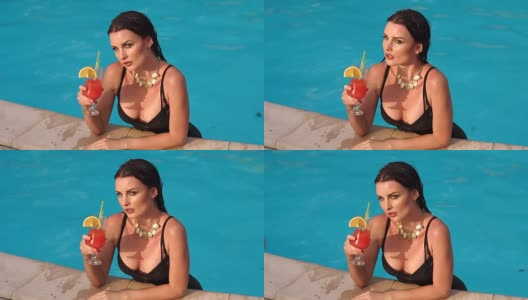 性感的黑发女子肖像与鸡尾酒在泳池。高清在线视频素材下载