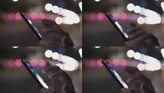 男子手持智能手机，在交通背景的散景圆灯下使用高清在线视频素材下载