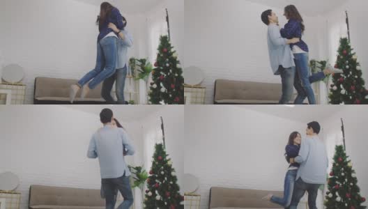 在圣诞树的背景下，年轻的亚洲情侣情侣在圣诞节和快乐的新年节日一起跳舞。圣诞节庆祝情人的概念。4 k慢动作。高清在线视频素材下载
