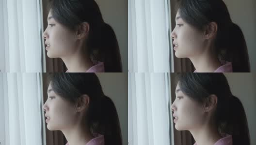 一个年轻的亚洲女人在早上透过窗户看风景的场景高清在线视频素材下载