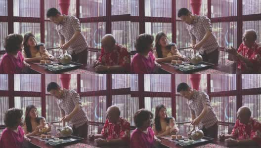 中国父亲在多代同堂期间奉上中国茶，在下午茶聚会期间享用传统的中秋节月饼和中国茶高清在线视频素材下载