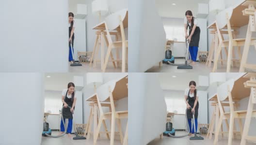 亚洲清洁服务女工清洁客厅在家里。美丽的年轻女孩管家清洁工穿围裙和吸尘肮脏的地板，家务和家务在房子。高清在线视频素材下载