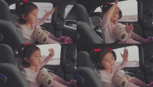蹒跚学步的小女孩在汽车座椅上唱歌跳舞。高清在线视频素材下载