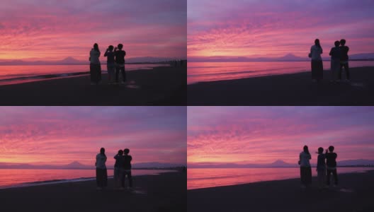 女性朋友和儿子在日落时分的海滩上拍照高清在线视频素材下载
