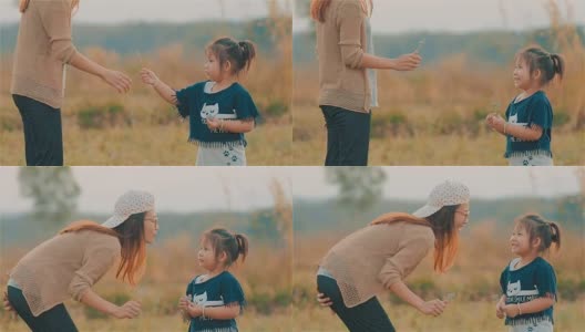 快乐的亚洲年轻母亲亲吻她的孩子的脸颊与模糊的田野一起高清在线视频素材下载